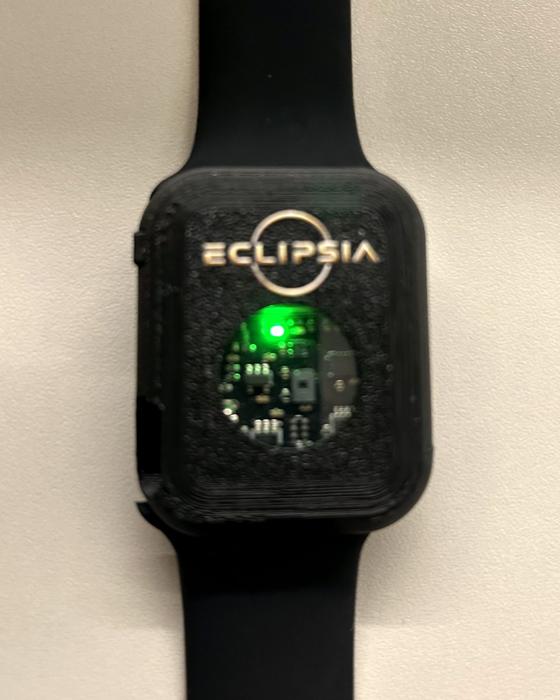 The Eclipsia prototype — a black wrist-worn case with an exposed sensor board and a lit indicator.